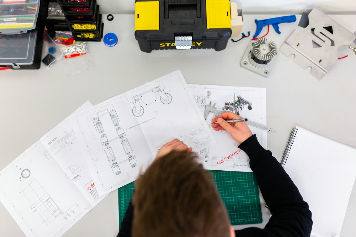 Feasibility review of a client drawing on a desk, red pen in hand